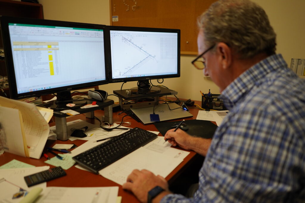 Man taking notes based on models on his computer screen while sitting at his desk
