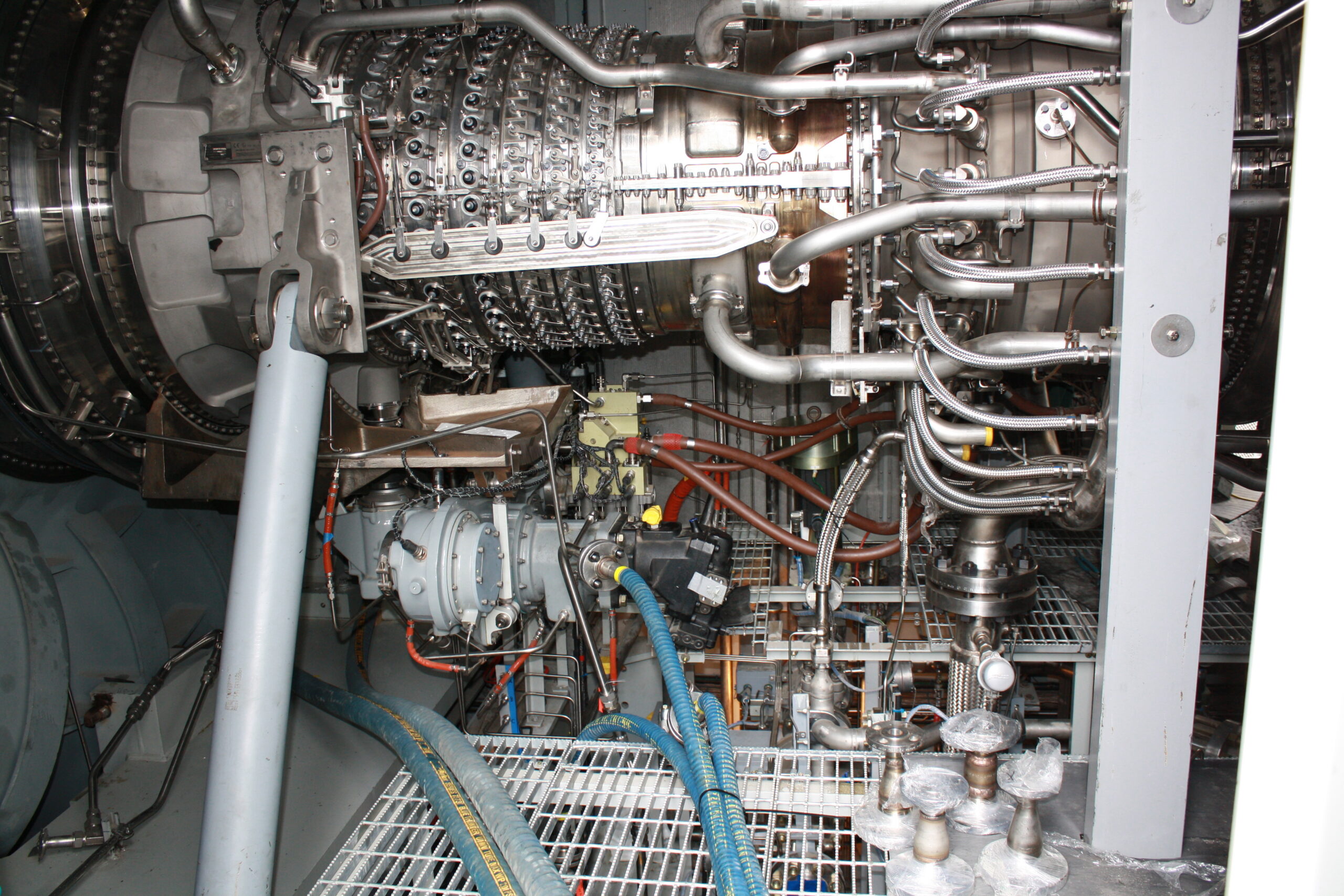 Close-up of a complex lube oil flushign equipment including gas turbine engine with numerous metallic pipes, cables, and mechanical components.